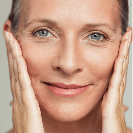Femme mature souriante, mains sur le visage, anti-âge global